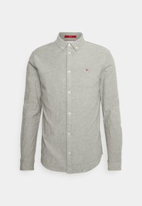 Harmaa pitkähihainen kauluksellinen nappipaita, jossa on pieni logo vasemmassa rinnassa, valmistettu teksturoidusta kankaasta.