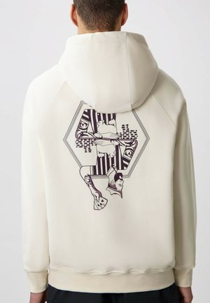 Crème-kleurige hoodie met een hexagonaal grafisch ontwerp op de rug, voorzien van geïllustreerde figuren en geprinte accenten. Zachte stof, relaxte pasvorm.