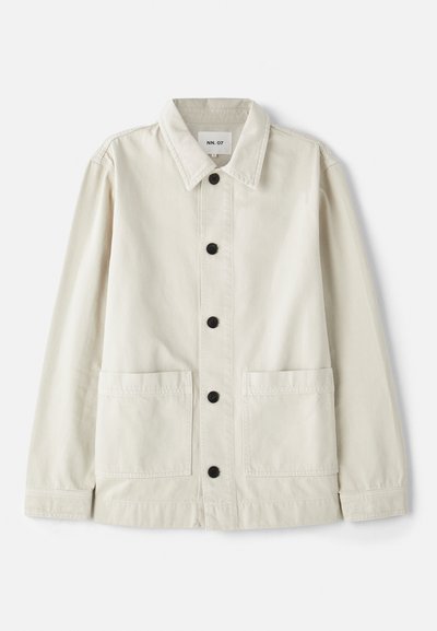 Light beige button-up jacket in durable cotton with a fold-down collar, two front pockets, and six black buttons. Smooth texture.