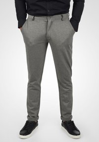 Grå bukser laget av teksturert stoff, med slim fit, flat front, sidelommer og svarte sidestriper, kombinert med svarte sneakers.