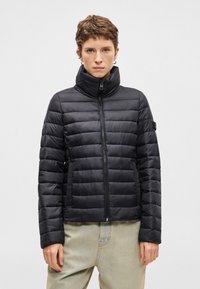 Juodas siuvinėtas pūkinis švarkas su aukštu apykakle ir priekinėmis užtrauktukais. Turintis horizontalų siuvinėjimą ir ilgomis rankovėmis, pagamintas iš lygaus, lengvo audinio.