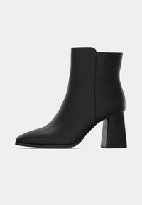 Μαύρη γυναικεία μπότες αστραγάλου με μυτερή μύτη, ομαλή συνθετική ύλη και υφή στον τακούνι. Αναβαθμισμένος σχεδιασμός με καθαρές γραμμές και κομψή σιλουέτα.