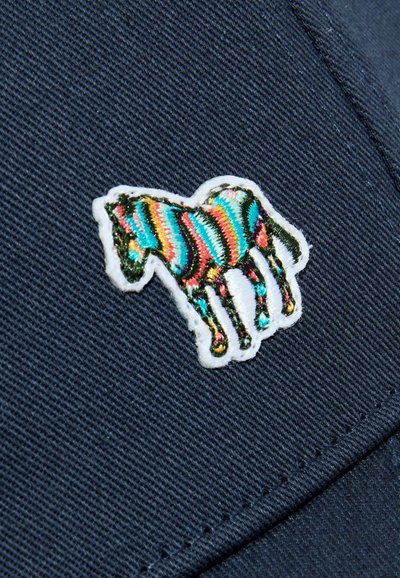 Patch de cheval brodé à rayures colorées cousu sur un tissu bleu foncé avec des lignes de couture visibles.