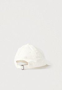 Șapcă albă din bumbac, cu vizor curbat, cataramă metalică reglabilă în spate și detalii cusute de-a lungul cusăturilor.