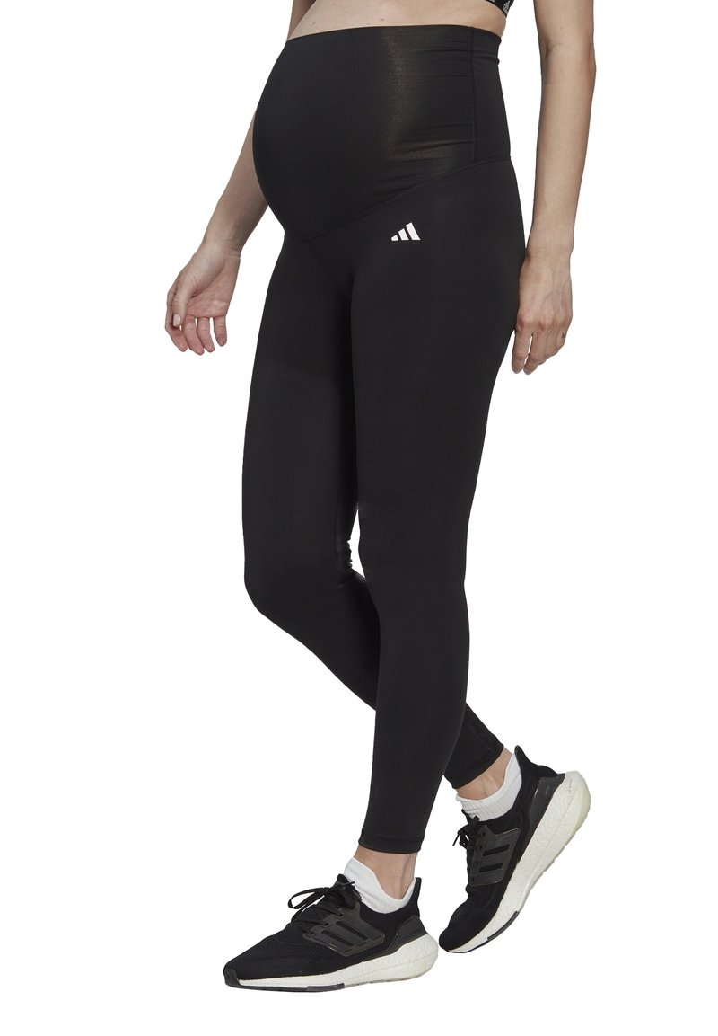 Leggings de maternité noirs avec une taille haute. Fabriqués en tissu extensible, avec un logo discret en trois bandes sur la cuisse gauche.