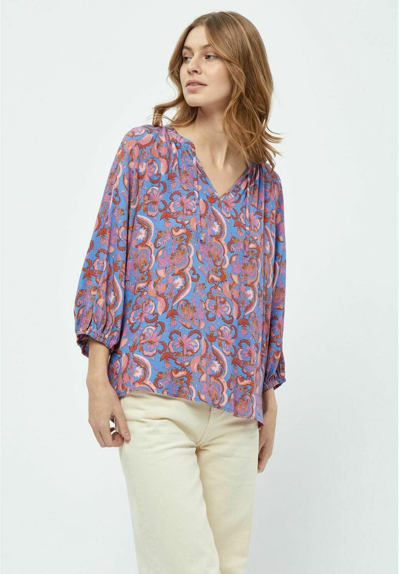 Blusa fluida blu con un motivo floreale colorato. Presenta un collo a V e maniche tre quarti con polsini elasticizzati.
