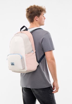 Sac à dos dans des tons rose clair, crème et gris. Comprend une poche zippée à l'avant et des accents bleus. Fabriqué en tissu durable avec des bretelles rembourrées.