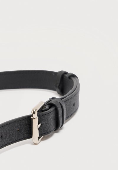 Μαύρη δερμάτινη ζώνη με ασημένια μεταλλική αγκράφα και ραμμένες άκρες, τοποθετημένη επίπεδα σε λευκό φόντο.