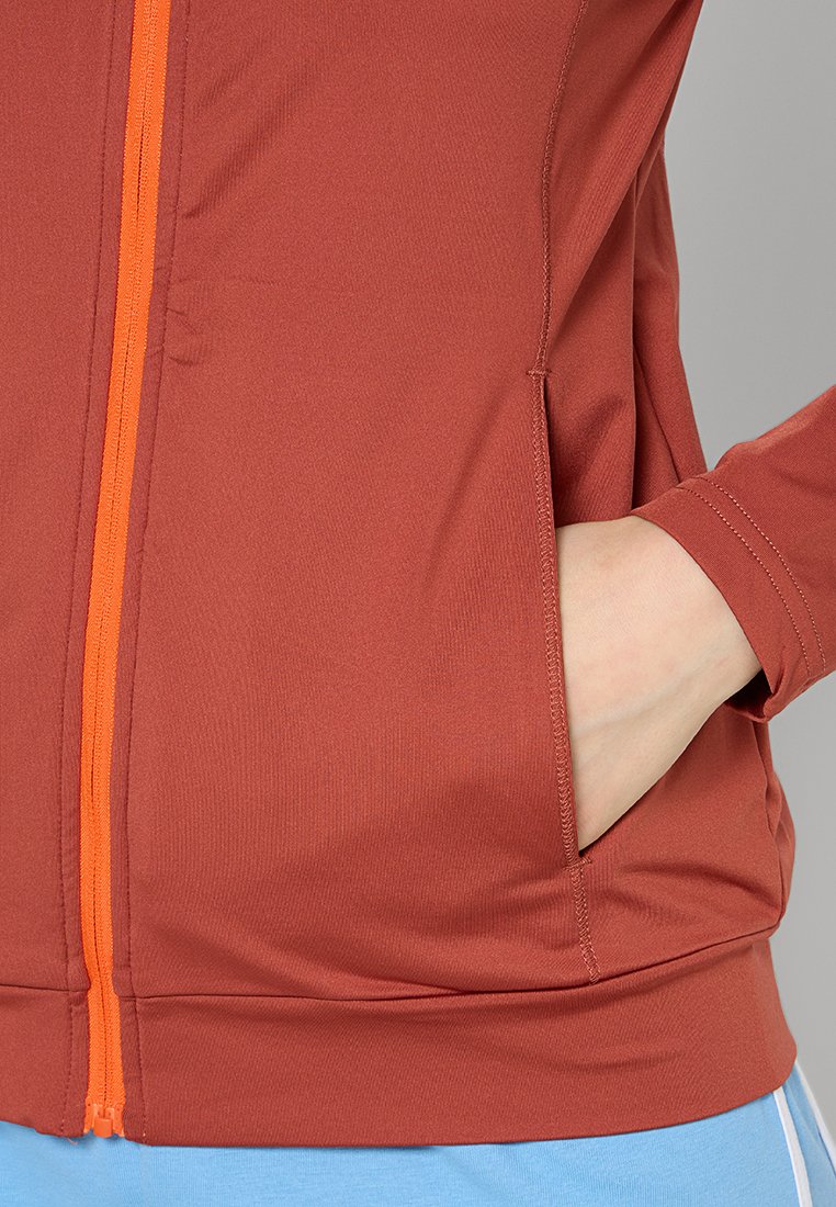 Chaqueta marrón con cremallera y acabado texturizado, con detalles en cremallera naranja, que cuenta con bolsillos laterales y una silueta ajustada.