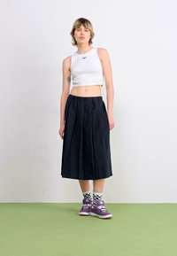 Hvit avkortet tanktopp kombinert med svarte stripete culottes med snor i midjen. Brukt med lilla sneakers og rutete sokker.