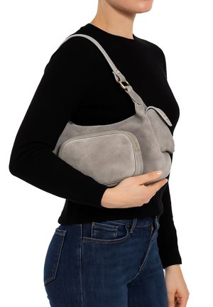 Borsa a spalla in suede grigio con dettagli in oro, dotata di una tasca frontale con zip e una forma arrotondata. La borsa viene indossata sotto il braccio.