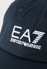 Șapcă bleumarin din bumbac, cu un design structurat, având brodat logo-ul alb "EA7 EMPORIO ARMANI" și accente distincte în relief.