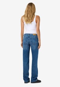 Jeans din denim albastru cu croi drept, spălare medie, design cu cinci buzunare și o patch din piele bej pe talie.