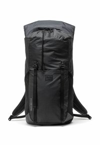 Sac à dos à carreaux noirs et gris avec une fermeture supérieure, des bretelles réglables et une surface texturée. L'étiquette avant porte le nom de la marque.