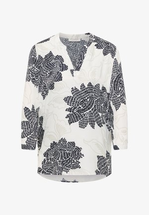 Hvid bluse med store blomsterprint i sort og lyst beige, V-hals og trekvartlange ærmer.