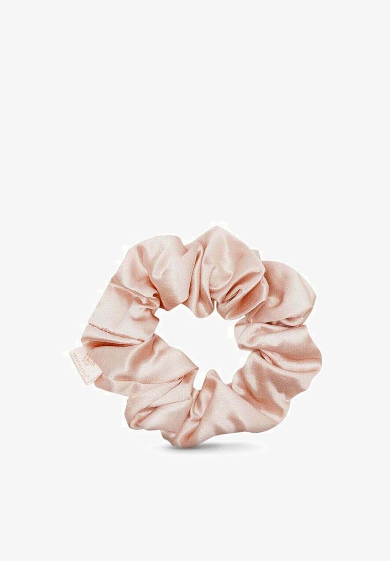 Scrunchie in satin di un delicato rosa; texture liscia, design arricciato, forma circolare con una leggera lucentezza, dotato di un piccolo etichetta.