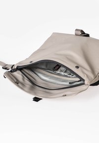 Borsa beige con finitura liscia e opaca. Il compartimento principale con zip rivela un rivestimento argentato, una tasca interna con zip e sezioni elasticizzate.