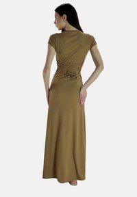 Robe maxi en tissu côtelé marron clair ; présente des manches courtes, un buste ajusté avec un dos froncé et un détail à nouer. Texture lisse.