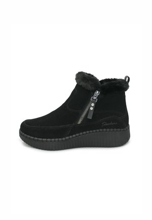 Stivaletti alla caviglia in suede nero con bordino in pelliccia sintetica, cerniera laterale e suola a cuneo rigata. Caratterizzati da una serie di accenti cuciti e branding.