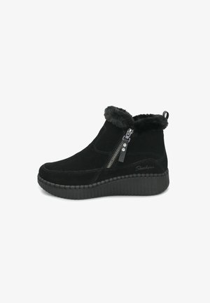 Stivaletti alla caviglia in suede nero con bordino in pelliccia sintetica, cerniera laterale e suola a cuneo rigata. Caratterizzati da una serie di accenti cuciti e branding.
