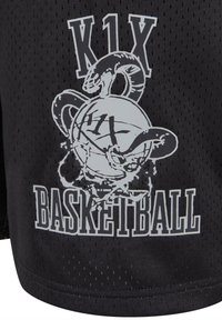 Pantaloni sportivi neri in tessuto a rete con una grafica grigia che presenta un design di un pallone da basket e un serpente. Il testo recita "K1X BASKETBALL."