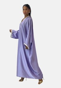 Paarse vloeiende kaftan met lange mouwen, voorzien van een V-hals en contrasterende bies langs de mouwen. Gladde textuur met een losse pasvorm.