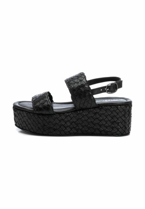 Sandali platform in pelle intrecciata nera con due ampie cinghie, punta tonda e cinghia alla caviglia regolabile. Presentano una suola spessa e texturizzata.