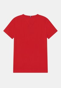 Camiseta corta de manga corta roja con cuello redondo, con costuras visibles en la parte trasera y un pequeño lazo de tela a rayas en el cuello.