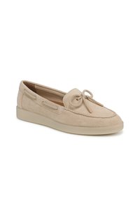 Beige suede moccasin shoe with lace detail, rounded toe, and a flat rubber sole. Features stitching accents and side ventilation holes.