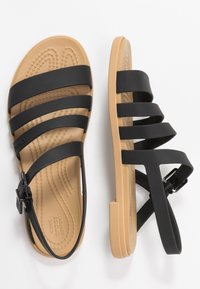 Svarta snörsandaler med en brun gummisula. Har en texturerad innersula och justerbar spännestraps för en säker passform.