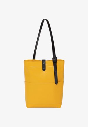 Bolsa tote de cuero amarillo con una correa adjustable negra, que cuenta con un cierre de botón y un bolsillo frontal. Textura suave y diseño minimalista.