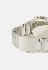 Stålur med en smalere armbånd, som har polerte og børstede metall-lenker, en glatt lås og en glatt rund kasse.