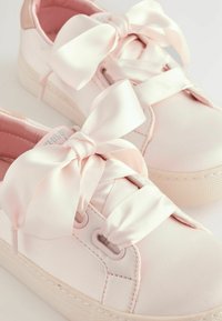 Baskets rose clair avec des lacets en satin, en matériau synthétique lisse, bout rond et semelle en caoutchouc blanc texturé.