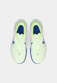 Ein Paar hellgrüne und blaue Nike-Laufschuhe, von oben auf einem weißen Hintergrund betrachtet.
