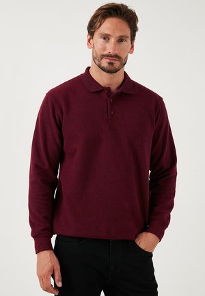 Camisa tipo polo de manga larga en color burdeos con cuello, que cuenta con una tapeta abotonada y puños de canalé, hecha de una tela texturizada.
