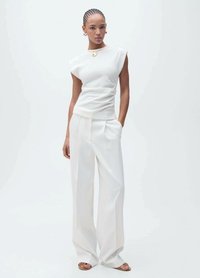 Top alb, ajustat, cu mâneci tip capă, design drapat, asociat cu pantaloni largi albi. Prezintă texturi simple, netede și hardware minim.