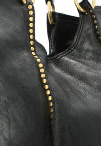 Borsa tote in pelle nera con superficie texturizzata, caratterizzata da borchie in tonalità oro lungo la cucitura e grandi accessori metallici per i manici.