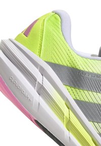 Zapatos deportivos con una parte superior de malla verde, rayas plateadas y acentos rosas. Presentan una suela blanca texturada con la marca "Cloudfoam+".
