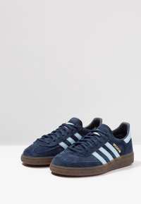 Zapatillas de ante azul marino con rayas azul claro, suela de goma marrón, puntera redondeada y texto dorado "SPEZIAL" en el lateral.