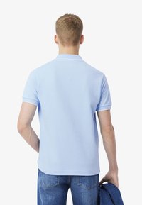 Ljusblå polo med en klassisk design, korta ärmar och krage. Texturerat tyg, ihop med denimjeans.