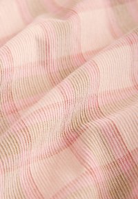 Zachte stof met golvende textuur met roze, beige en lichtbruine dunne strepen in een close-up weergave.