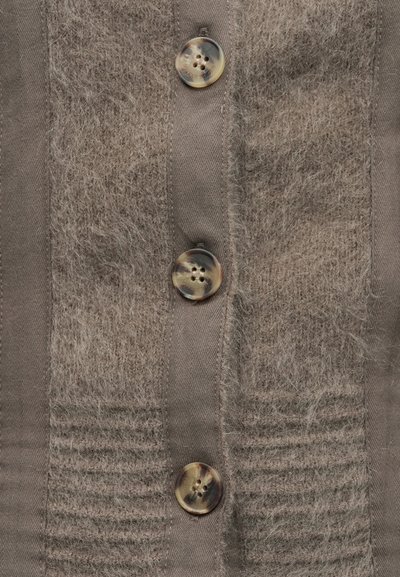 Prim-plan al unui cardigan maro pufos cu trei nasturi mari rotunzi, de tip scoică țestoasă, pe centru.