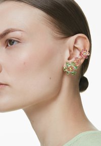Guldtonede øreringe præsenterer en stor grøn og pink blomst med ædelsten samt en mindre pink blomsterstud, begge med intrikate detaljer og kurver.