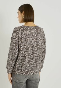 Jersey de manga larga con estampado de leopardo, ajuste holgado, escote redondo y tejido suave y texturizado en tonos marrones y beige.