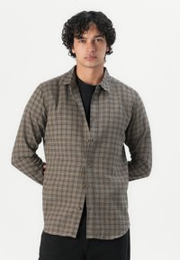 Brown plaid shirt made of lightweight fabric, featuring a button-down front, long sleeves, and a relaxed fit.
