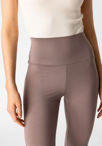 Leggings a vita alta in mauve tenue, caratterizzati da una texture liscia e elastica con un design a coste, ideali per il comfort e la flessibilità.