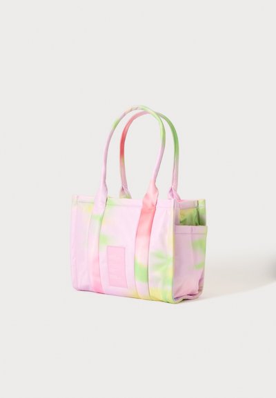 Sac cabas tie and dye rose pastel, vert et jaune avec double poignées et poches latérales, debout sur un fond uni clair.