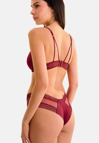 Ensemble de soutien-gorge bordeaux et culotte assortie avec bretelles ajustables, détails en dentelle à la taille et finition lisse. La vue arrière montre des accents en mesh.