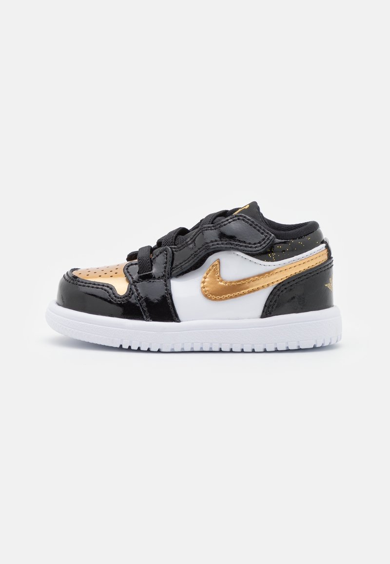 Baskets basses Nike en noir, blanc et or métallique avec lacets et semelle blanche, vues de côté sur un fond uni.