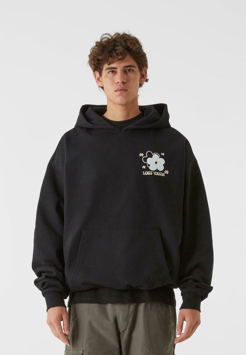 Fekete kapucnis pulóver, pamutból készült, elől zseb található, és egy fehér virág grafika "LOST YOUTH" felirattal a mellrészen.